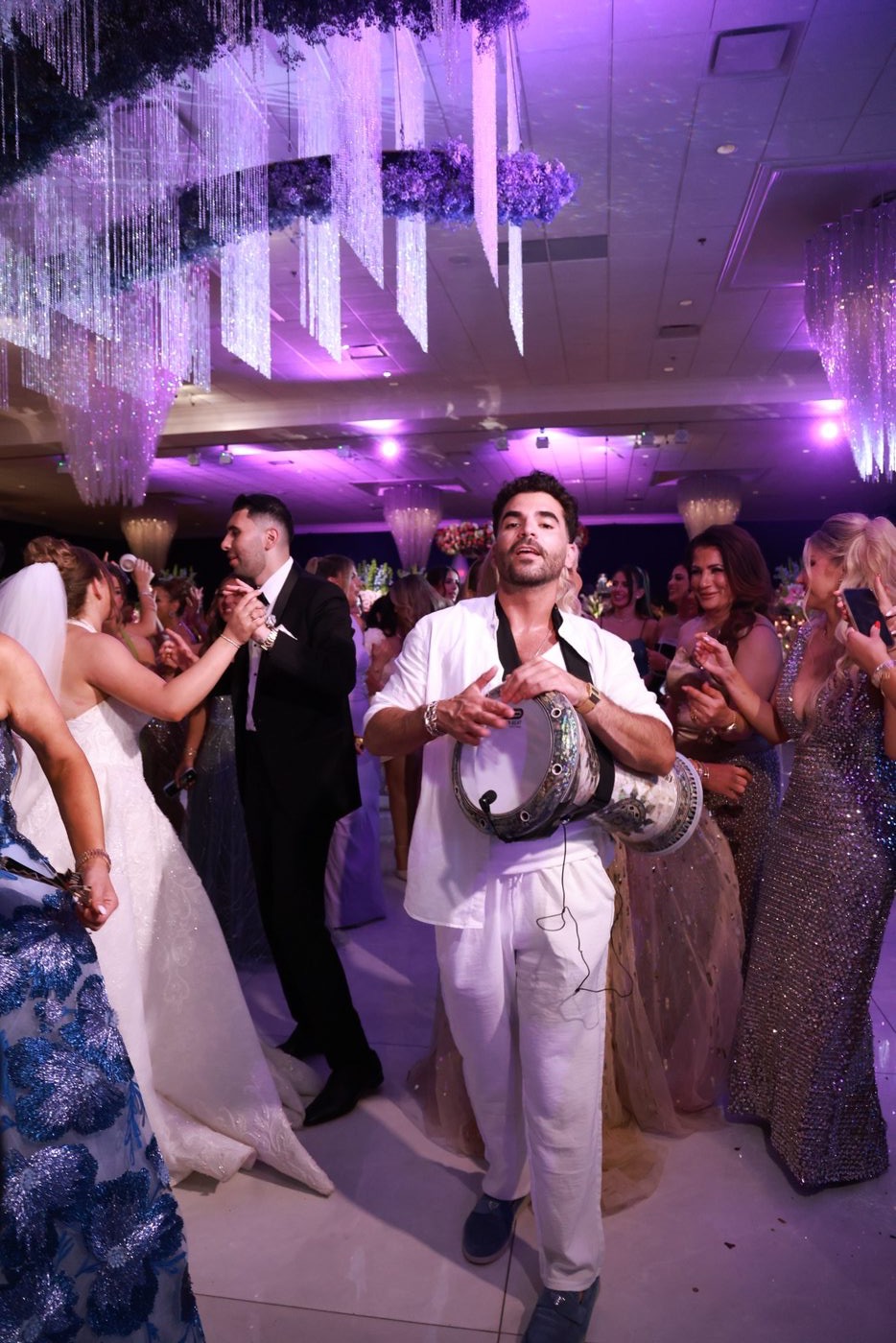 A Prestige Brothers performer with a derbake on a packed dance floor under stage lighting