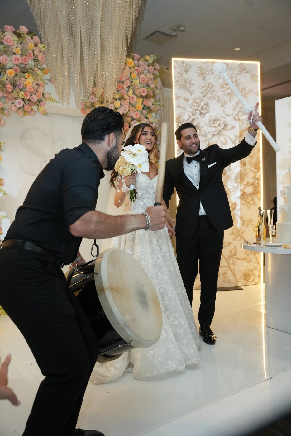 A drummer playing as a couple raise a sparkler wand at their reception