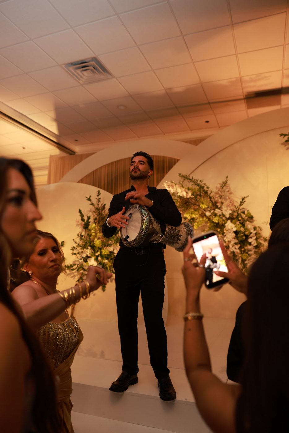 A derbake player performing as guests film the entrance