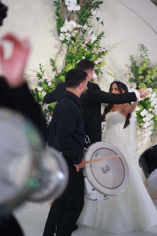 Prestige Brothers drummers flanking a couple at a floral ceremony backdrop